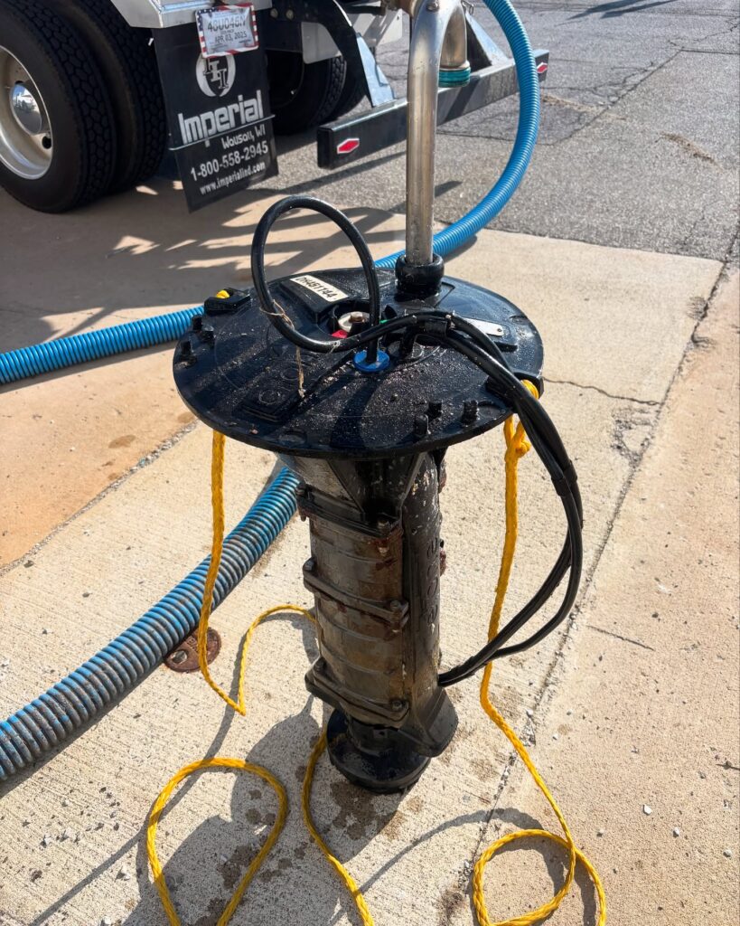 Industrial pump assembly with blue hoses and yellow ropes outdoors near a truck, likely for fluid transfer or loading. - arwwm - arwwm