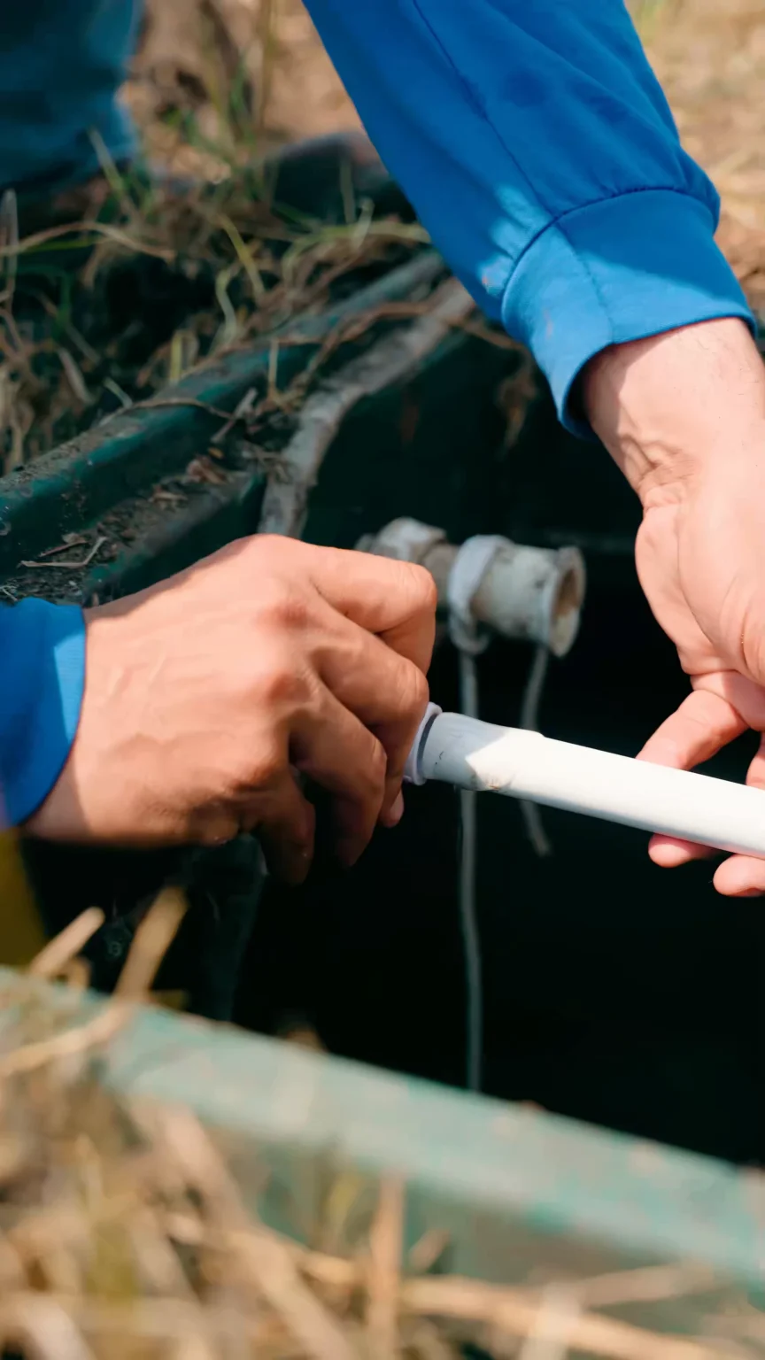 Pipe repair - ARWWM - ARWWM Two hands gripping a white pvc pipe during outdoor plumbing work beside a trench and dirt. - arwwm - arwwm
